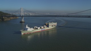 DFKSF09_051 - 5K aerial stock footage track a cargo ship sailing away from the Bay Bridge, San Francisco, California