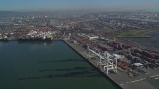 DFKSF09_056 - 5K aerial stock footage pan across the Port of Oakland to approach cargo cranes, California