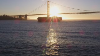 DFKSF10_021 - 5K aerial stock footage of a cargo ship near Golden Gate Bridge, San Francisco, California, sunset