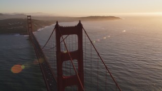 DFKSF10_023 - 5K aerial stock footage of flying over Golden Gate Bridge, reveal cargo ship, San Francisco, California, sunset