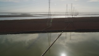 DFKSF11_009 - 5K aerial stock footage of flying by power lines and tilting to marshland below, Sunnyvale, California