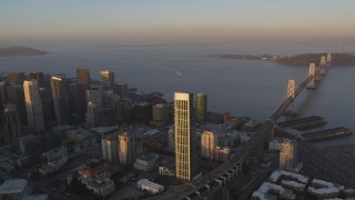 DFKSF14_002 - 5K aerial stock footage flyby Bay Bridge and One Rincon Hill skyscraper, reveal Downtown San Francisco, California, sunset