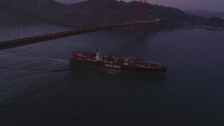 DFKSF14_043 - 5K aerial stock footage of a cargo ship sailing under Golden Gate Bridge, San Francisco, California, twilight