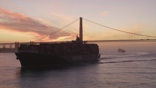 DFKSF14_045 - 5K aerial stock footage fly over a cargo ship to approach the Golden Gate Bridge, San Francisco, California, twilight