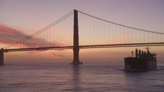 DFKSF14_047 - 5K aerial stock footage of flying by famous Golden Gate Bridge, reveal oil tanker, San Francisco, California, twilight
