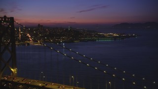 DFKSF14_074 - 5K aerial stock footage of flying over Bay Bridge while focusing on Coit Tower, North Beach, San Francisco, California, twilight