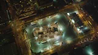 DFKSF14_080 - 5K aerial stock footage of tilting to bird's eye view of a Greyhound bus depot, Downtown San Francisco, California, night