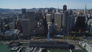 DFKSF15_013 - 5K aerial stock footage of flying away from the Ferry Building and skyscrapers in Downtown San Francisco, California