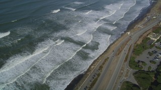 DFKSF15_044 - 5K aerial stock footage video of a reverse view of ocean waves and Great Highway, Lakeshore District, San Francisco, California