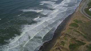 DFKSF15_045 - 5K aerial stock footage of waves rolling toward coastal cliffs in the Lakeshore District, San Francisco, California