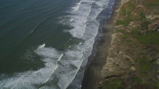 DFKSF15_046 - 5K aerial stock footage fly away from waves rolling toward beach and cliffs in the Lakeshore District, San Francisco, California