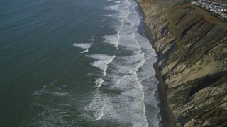 DFKSF15_048 - 5K aerial stock footage of flying away from ocean waves rolling toward coastal cliffs, Daly City, California