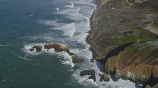 DFKSF15_050 - 5K aerial stock footage fly away from waves rolling into coastal cliffs and rock formations, Daly City, California