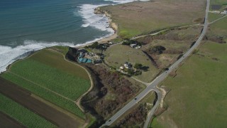 DFKSF15_112 - 5K aerial stock footage of a reverse view of Highway 1 on the coast, revealing crop fields, Davenport, California