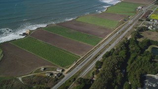 DFKSF15_113 - 5K aerial stock footage of flying away from Highway 1 along the coast and crop fields, Davenport, California
