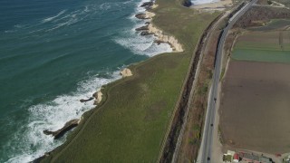 DFKSF15_115 - 5K aerial stock footage of a reverse view of Highway 1 coastal road and train tracks, Davenport, California