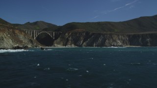 DFKSF16_072 - 5K stock footage aerial video of flying by coastal rock formation, revealing Bixby Creek Bridge, Big Sur, California