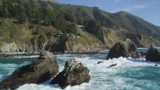 DFKSF16_125 - 5K stock footage aerial video tilt from the ocean to reveal rock formations, home atop coastal cliff, Big Sur, California