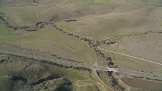 DFKSF16_144 - 5K aerial stock footage of a reverse view of grassy hills, reveal country road in San Luis Obispo County, California