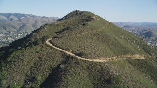 DFKSF16_159 - 5K aerial stock footage tilt up slope of a mountain with dirt roads in San Luis Obispo, California