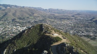 DFKSF16_160 - 5K aerial stock footage of flying over a mountain with dirt roads, revealing San Luis Obispo, California