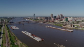 DX0001_000580 - 5.7K aerial stock footage side view of Mississippi River and barges with city in the distance, Downtown St. Louis, Missouri