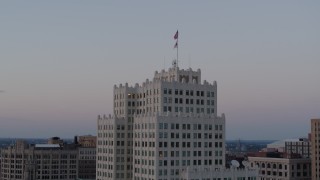 DX0001_000886 - 5.7K aerial stock footage of flags atop a downtown apartment building at twilight, Downtown St. Louis, Missouri