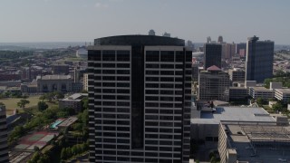 DX0001_001097 - 5.7K aerial stock footage of circling the top of a Crown Center office building in Kansas City, Missouri, skyline in background