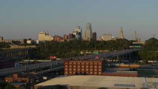 DX0001_001162 - 5.7K aerial stock footage of the city's skyline seen while flying by freeway at sunset in Downtown Kansas City, Missouri