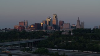DX0001_001180 - 5.7K aerial stock footage reverse view of city skyline reflecting the setting sun in Downtown Kansas City, Missouri, twilight