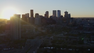 DX0001_001616 - 5.7K aerial stock footage descend with view of the sun behind the city skyline at sunrise in Downtown Denver, Colorado