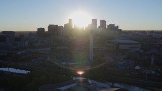 DX0001_001623 - 5.7K aerial stock footage of sun and city skyline, seen from theme park and arena at sunrise in Downtown Denver, Colorado