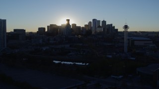 DX0001_001624 - 5.7K aerial stock footage of sun and city skyline, seen while flying by theme park and arena at sunrise in Downtown Denver, Colorado