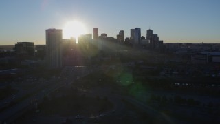 DX0001_001625 - 5.7K aerial stock footage of sun and city skyline, seen while flying by skyscraper at sunrise in Downtown Denver, Colorado