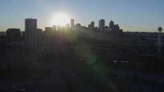 DX0001_001626 - 5.7K aerial stock footage of sun and city skyline, seen while descending near a skyscraper at sunrise in Downtown Denver, Colorado