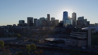DX0001_001631 - 5.7K aerial stock footage flyby the rising sun behind the city skyline, reveal the arena in Downtown Denver, Colorado