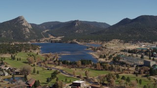 DX0001_001981 - 5.7K aerial stock footage fly away from Lake Estes, by golf course and green mountains in Estes Park, Colorado
