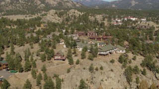 DX0001_002006 - 5.7K aerial stock footage flying away from rural hillside homes near rugged mountains in Estes Park, Colorado