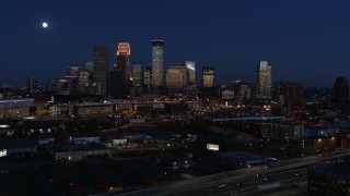DX0001_002284 - 5.7K aerial stock footage descend with view of moon above city's skyline at twilight, Downtown Minneapolis, Minnesota