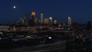 DX0001_002285 - 5.7K aerial stock footage ascend with view of moon above city's skyline at twilight, Downtown Minneapolis, Minnesota