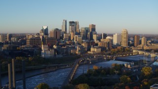 DX0001_002295 - 5.7K aerial stock footage of flying by the city skyline across the Mississippi River at sunrise, Downtown Minneapolis, Minnesota