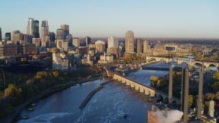 DX0001_002299 - 5.7K aerial stock footage flying bridge and river with view of skyline at sunrise, Downtown Minneapolis, Minnesota
