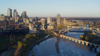 DX0001_002300 - 5.7K aerial stock footage passing bridge and river to reveal power plant, with view of skyline at sunrise, Downtown Minneapolis, Minnesota