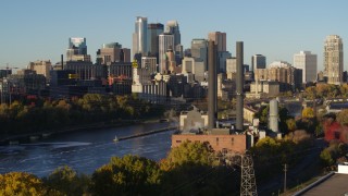 DX0001_002327 - 5.7K aerial stock footage descend by riverfront power plant at sunrise, with skyline in background, Downtown Minneapolis, Minnesota