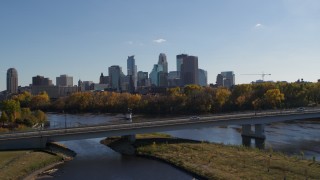 DX0001_002449 - 5.7K aerial stock footage white car crossing bridge over river with view of city skyline, Downtown Minneapolis, Minnesota