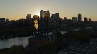 DX0001_002520 - 5.7K aerial stock footage of the city skyline across the river while flying by a power plant at sunset, Downtown Minneapolis, Minnesota