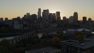 DX0001_002528 - 5.7K aerial stock footage view of city skyline during descent by bridge and river at sunset, Downtown Minneapolis, Minnesota