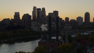 DX0001_002542 - 5.7K aerial stock footage descend by power plant at sunset with view of skyline of Downtown Minneapolis, Minnesota