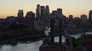 DX0001_002552 - 5.7K aerial stock footage flyby power plant and river to focus on skyline at sunset, Downtown Minneapolis, Minnesota
