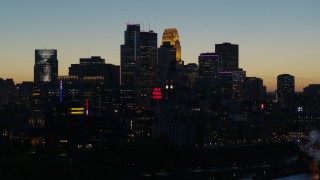 DX0001_002584 - 5.7K aerial stock footage pass by smoke stacks and the city skyline lit for the night at twilight, Downtown Minneapolis, Minnesota